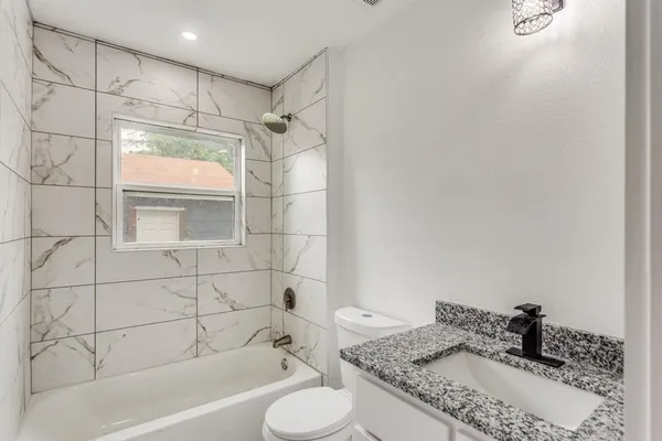 a bathroom with a granite countertop sink toilet and shower