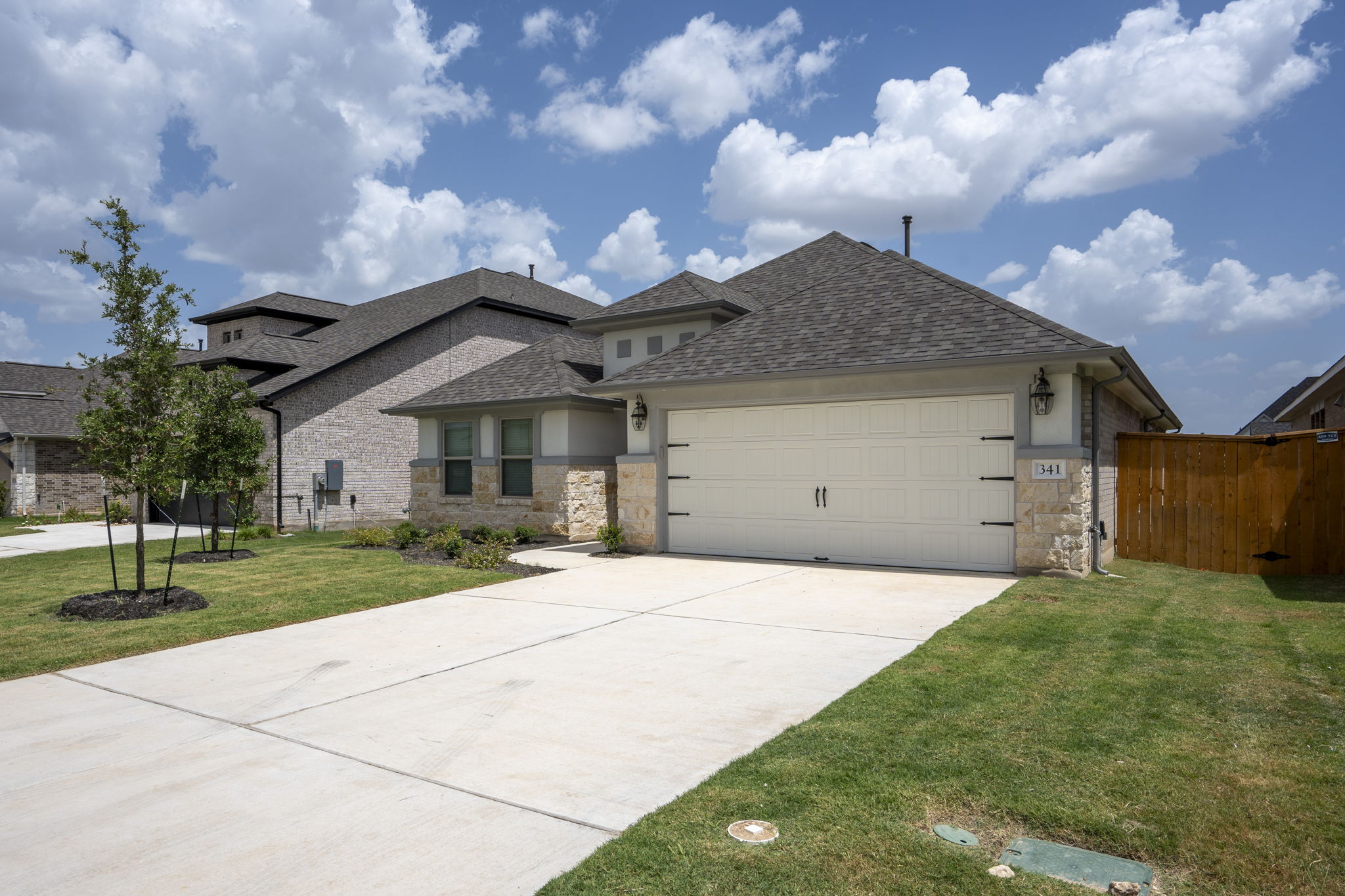 341 Fawn Riv Run Kyle, TX 78640 - Photo 2 of 29 View of front of property with stone siding, concrete driveway, a front lawn, and an attached garage