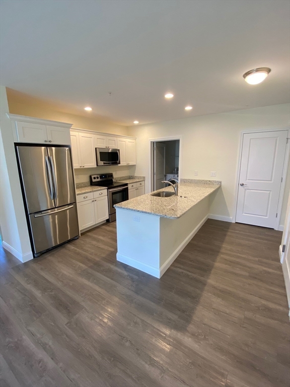 47 Saunders Street, Unit 47 North Andover, MA 01845 - Photo 3 of 11 a large white kitchen with wooden floor and stainless steel appliances