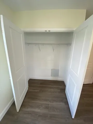 a view of an empty room with wooden floor and stairs