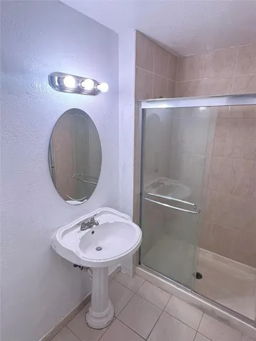 a bathroom with a sink shower and a mirror