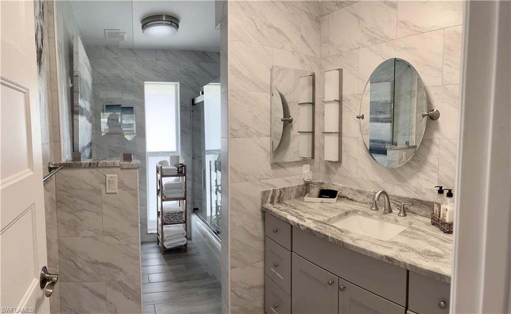 306 Palm Drive, Unit 2 Naples, FL 34112 - Photo 14 of 25 a en suite bathroom with a granite countertop sink and a mirror