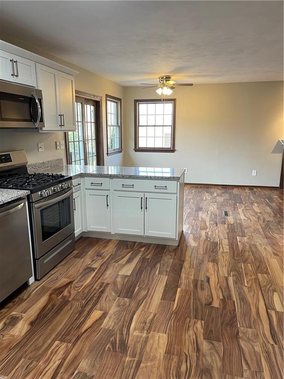 690 Adele Drive North Huntingdon, PA 15642 - Photo 9 of 25 a kitchen with granite countertop a stove a sink and white cabinets with wooden floor