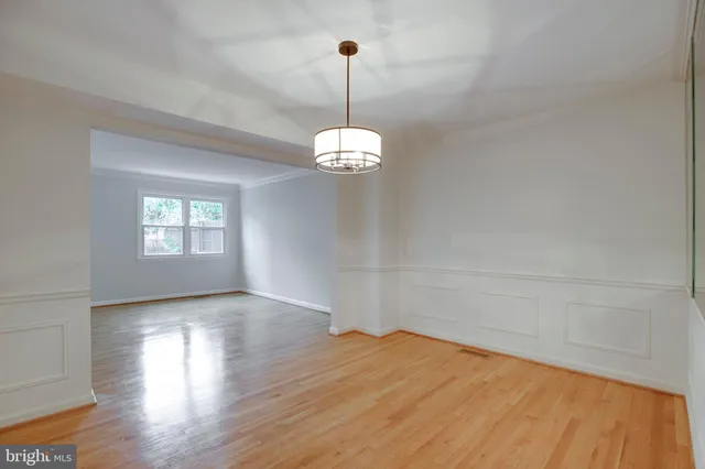 a view of an empty room with wooden floor and a fireplace
