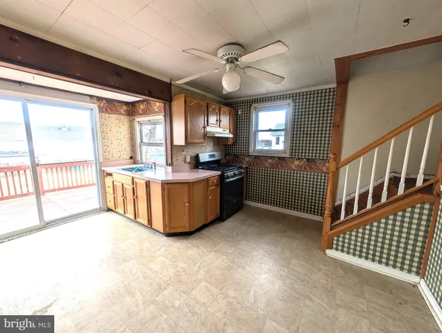 a view of an empty room with window and kitchen view