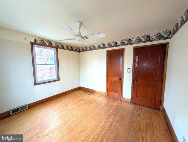 an empty room with wooden floor closet and windows