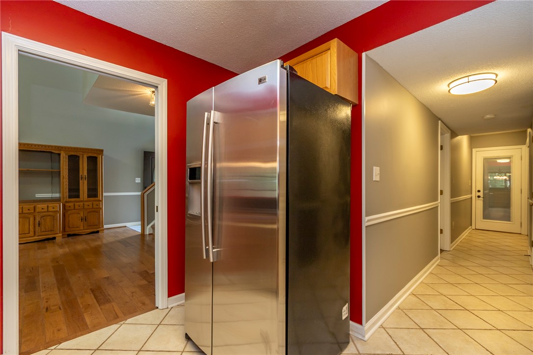 1302 Leeward Road Anderson, SC 29625 - Photo 13 of 50 A side-by-side stainless steel refrigerator integrates with bright red accent walls and tile flooring.
