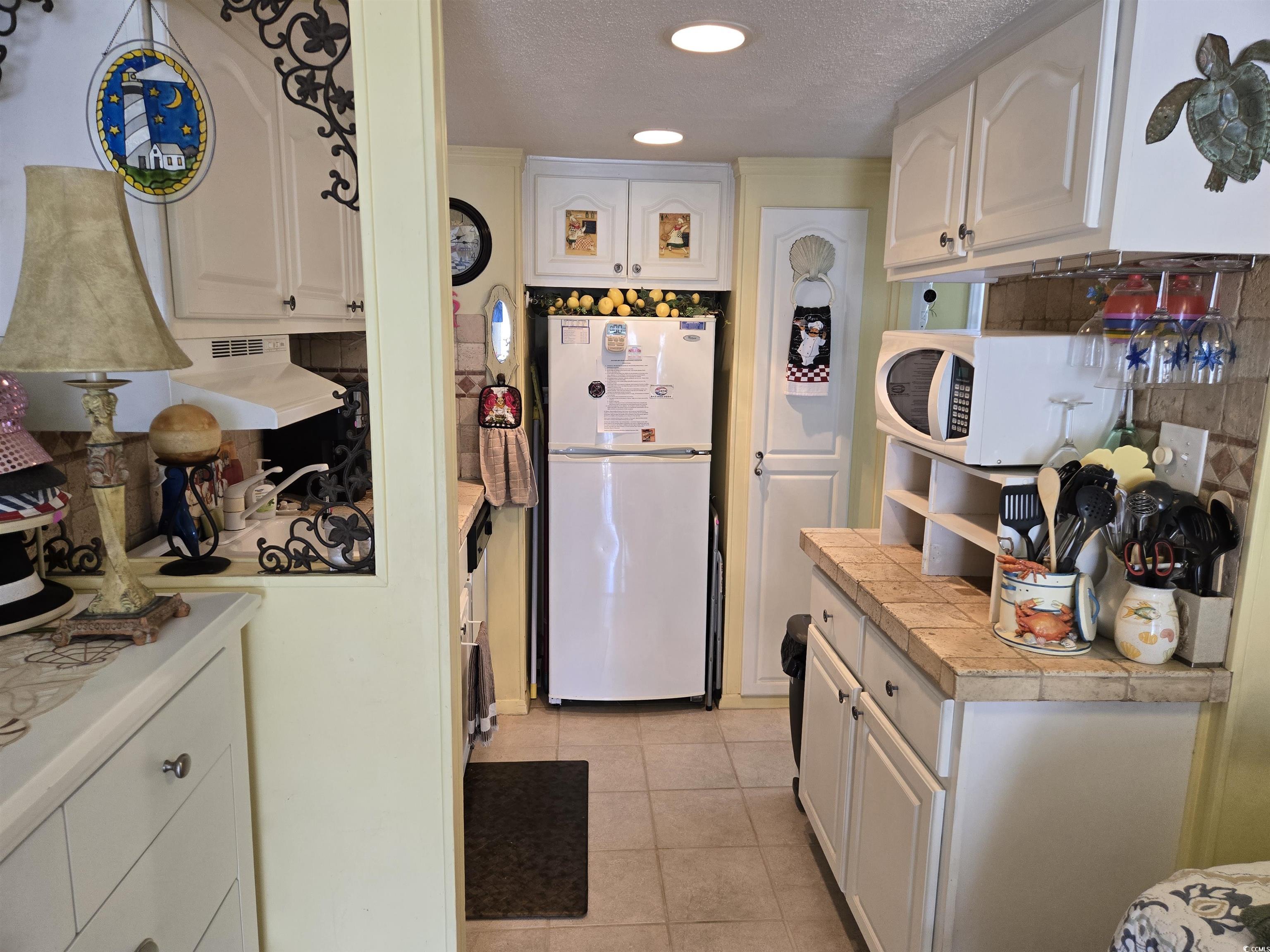 2204 Perrin Drive, Unit 3 North Myrtle Beach, SC 29582 - Photo 20 of 39 Kitchen featuring tile counters, white appliances, white cabinets, and light tile patterned floors