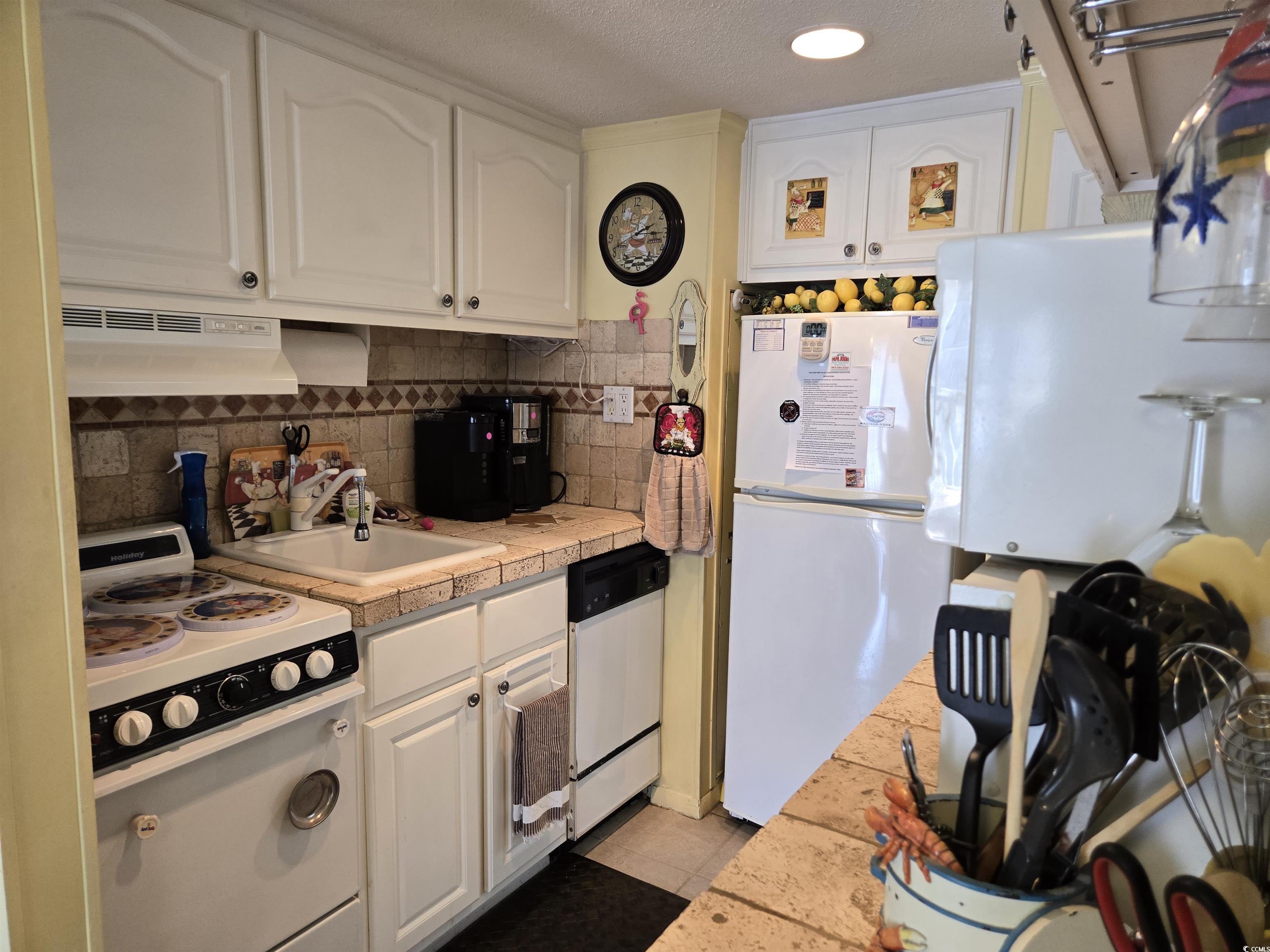 2204 Perrin Drive, Unit 3 North Myrtle Beach, SC 29582 - Photo 21 of 39 Kitchen with white appliances, light tile patterned floors, sink, white cabinetry, and decorative backsplash