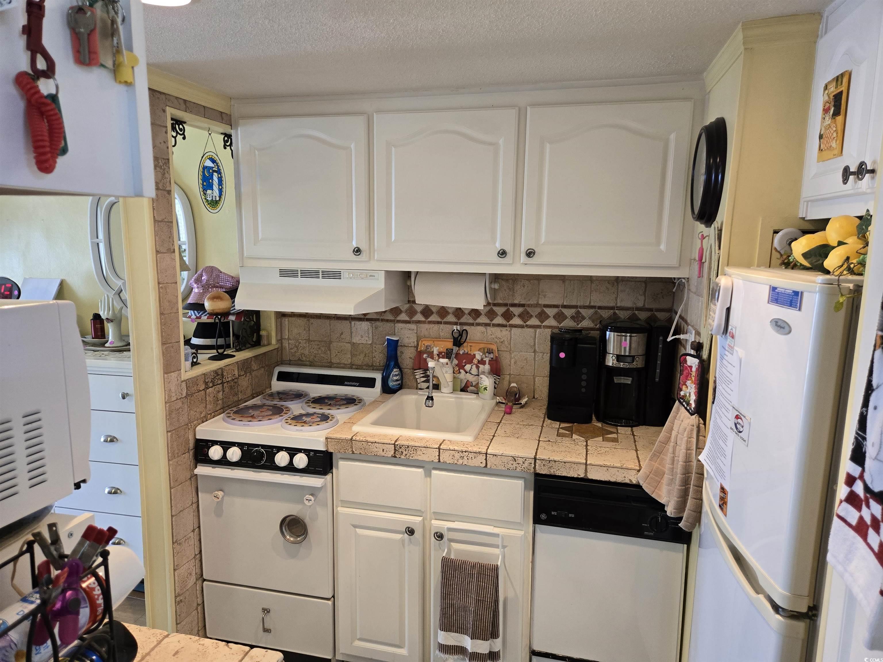 2204 Perrin Drive, Unit 3 North Myrtle Beach, SC 29582 - Photo 22 of 39 Kitchen with tile countertops, sink, white appliances, a textured ceiling, and white cabinets