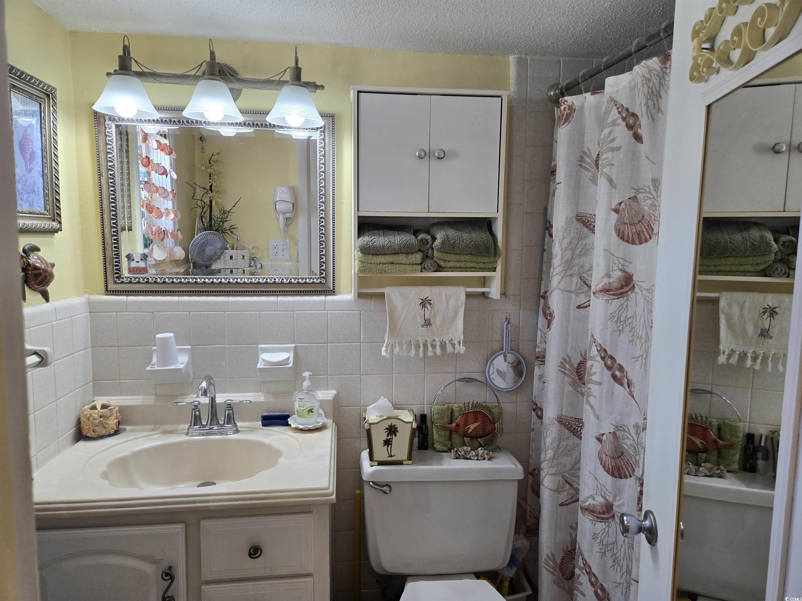 2204 Perrin Drive, Unit 3 North Myrtle Beach, SC 29582 - Photo 23 of 39 Bathroom with curtained shower, toilet, tile walls, a textured ceiling, and vanity