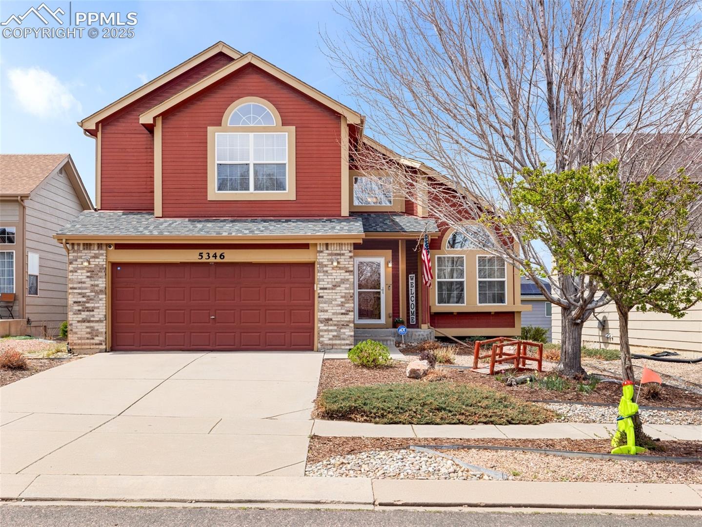 5346 Gentle Wind Road Colorado Springs, CO 80922 - Photo 1 of 28 Traditional home featuring concrete driveway, brick siding, a shingled roof, and a garage
