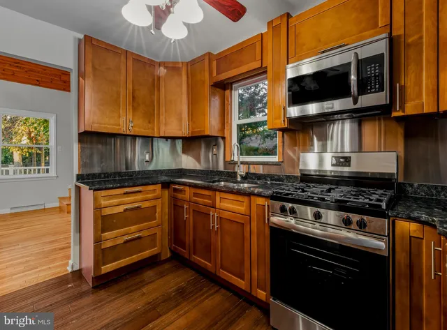 a kitchen with stainless steel appliances granite countertop a stove a sink and a microwave