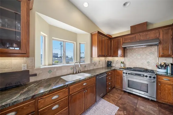 a kitchen with stainless steel appliances granite countertop a refrigerator a stove and a wooden floors