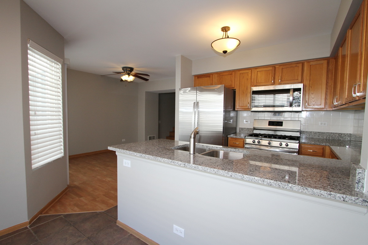 3159 Cambria Court Aurora, IL 60503 - Photo 7 of 20 a kitchen with stainless steel appliances granite countertop a sink a stove and a refrigerator