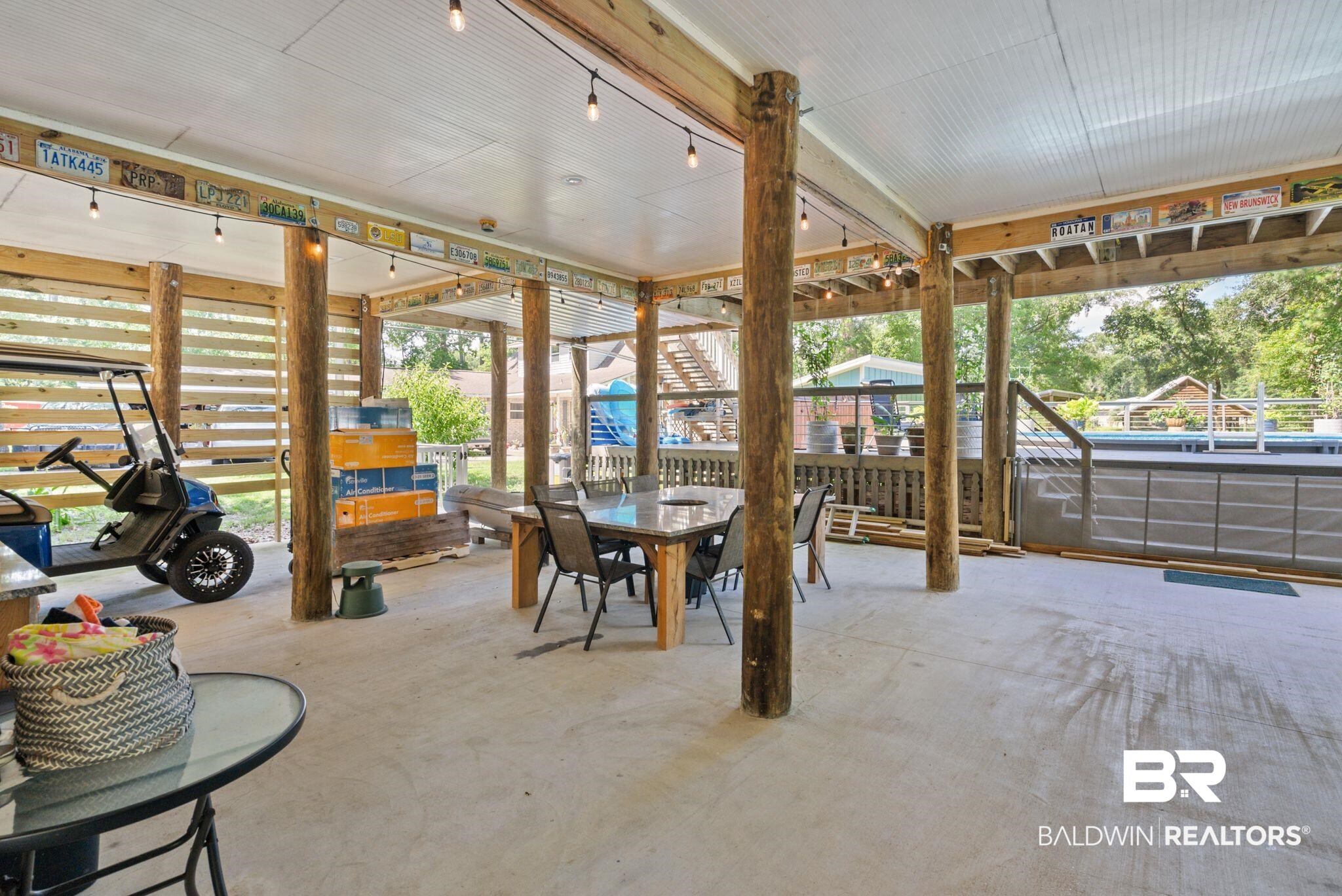 7266 Franklin Road Foley, AL 36535 - Photo 53 of 64 Expansive covered patio featuring a concrete floor, exposed wood support beams, string lighting, and a slatted wood privacy screen