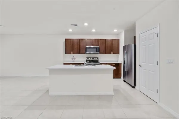 a kitchen with stainless steel appliances a stove top oven a sink a refrigerator and a window