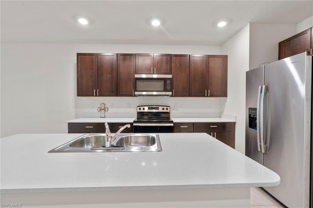 15535 Wildflower Circle Naples, FL 34119 - Photo 4 of 33 a kitchen with stainless steel appliances granite countertop a sink a stove a refrigerator a washer dryer and white cabinets