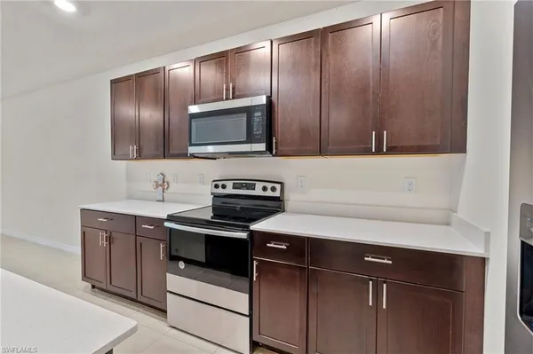 a kitchen with stainless steel appliances granite countertop a sink a stove a refrigerator a washer dryer and white cabinets