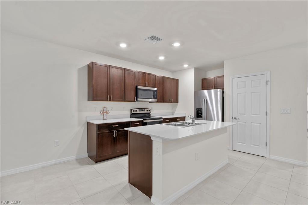 15535 Wildflower Circle Naples, FL 34119 - Photo 7 of 33 a kitchen with stainless steel appliances a stove refrigerator sink and microwave