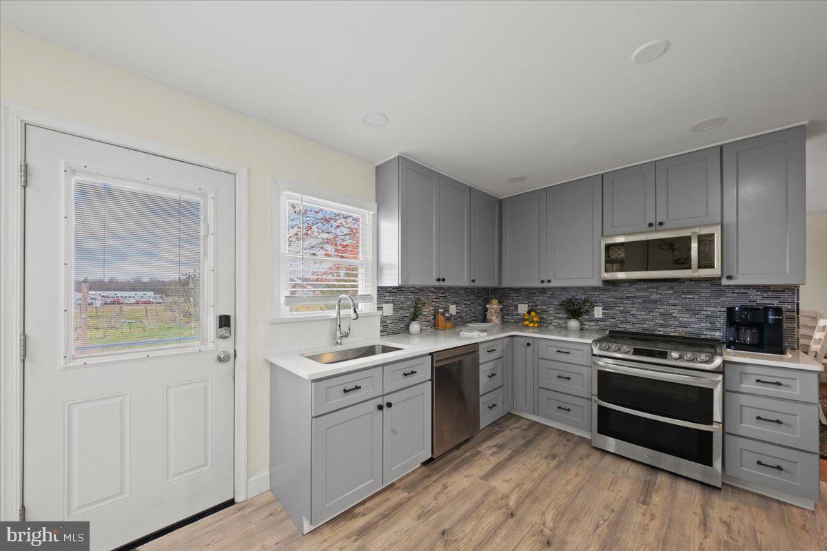 484 Centerton Road Bridgeton, NJ 08302 - Photo 11 of 49 a kitchen with stainless steel appliances granite countertop a stove top oven a sink dishwasher and white cabinets with wooden floor