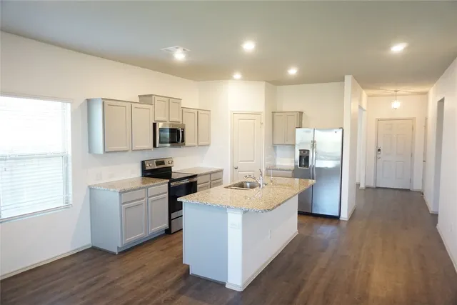 a large kitchen with stainless steel appliances granite countertop a lot of counter space and wooden floor