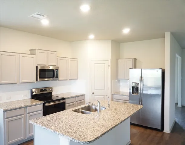 a kitchen with granite countertop a refrigerator and a sink