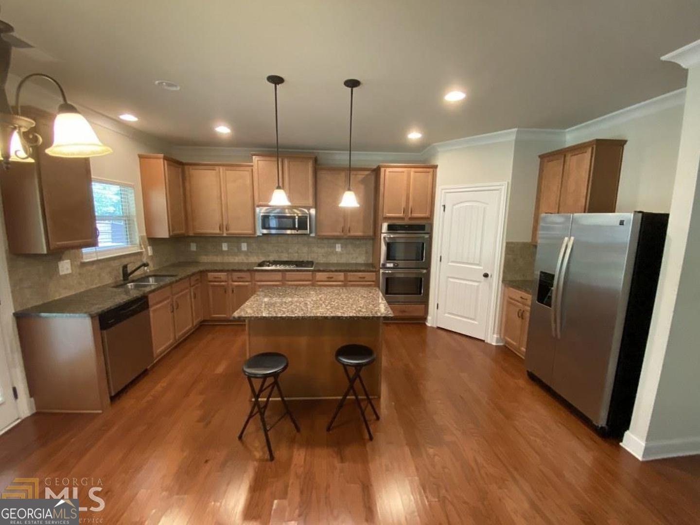 9159 Dover Street Lithia Springs, GA 30122 - Photo 2 of 23 a kitchen with stainless steel appliances granite countertop a refrigerator a sink a stove a microwave a dining table and chairs