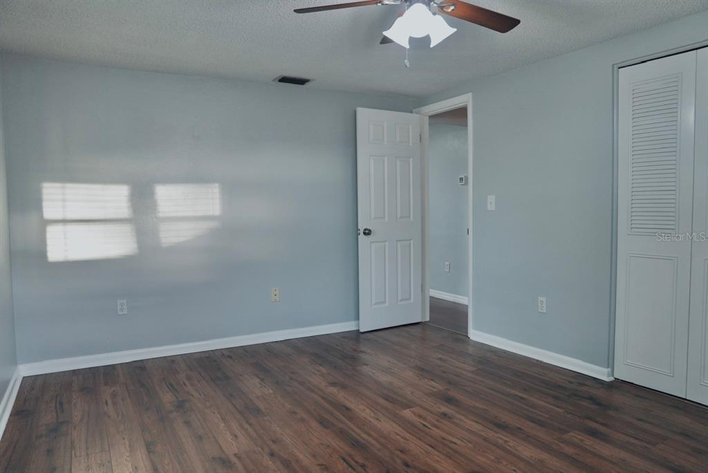 7944 Yucca Drive New Port Richey, FL 34653 - Photo 15 of 26 an empty room with wooden floor chandelier fan and windows
