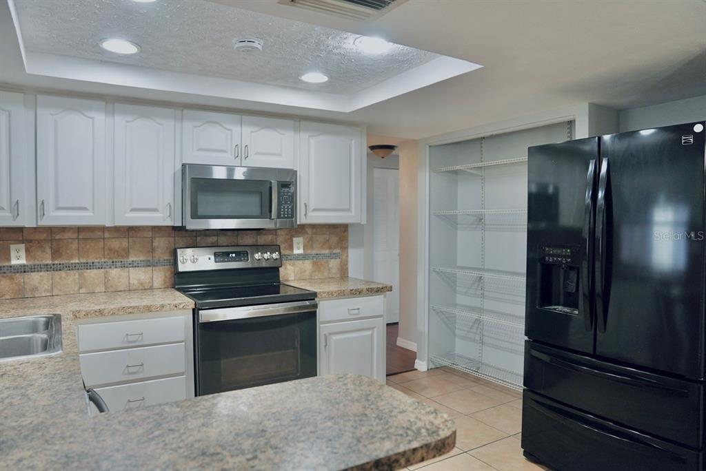 7944 Yucca Drive New Port Richey, FL 34653 - Photo 5 of 26 a kitchen with a refrigerator stove and cabinets