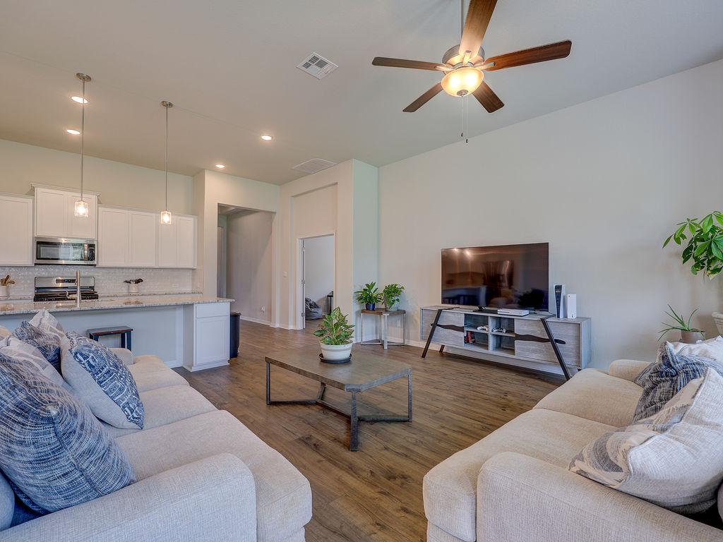 229 Heartleaf Road San Marcos, TX 78666 - Photo 39 of 40 An open floorplan seamlessly connects the kitchen and living room, featuring a sleek breakfast bar and hardwood-style flooring.