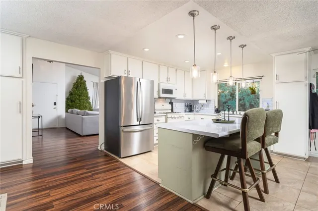 a kitchen with stainless steel appliances a refrigerator a sink a stove a dining table and chairs