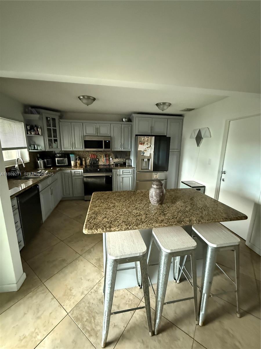 13060 Southwest 263rd Terrace Homestead, FL 33032 - Photo 11 of 30 a kitchen with kitchen island a counter top space appliances and cabinets