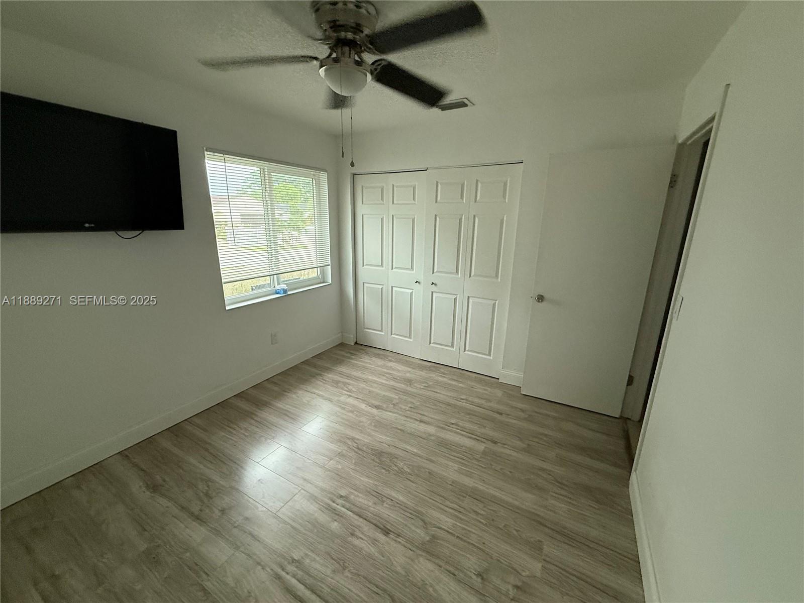 13060 Southwest 263rd Terrace Homestead, FL 33032 - Photo 13 of 30 an empty room with wooden floor fan and windows