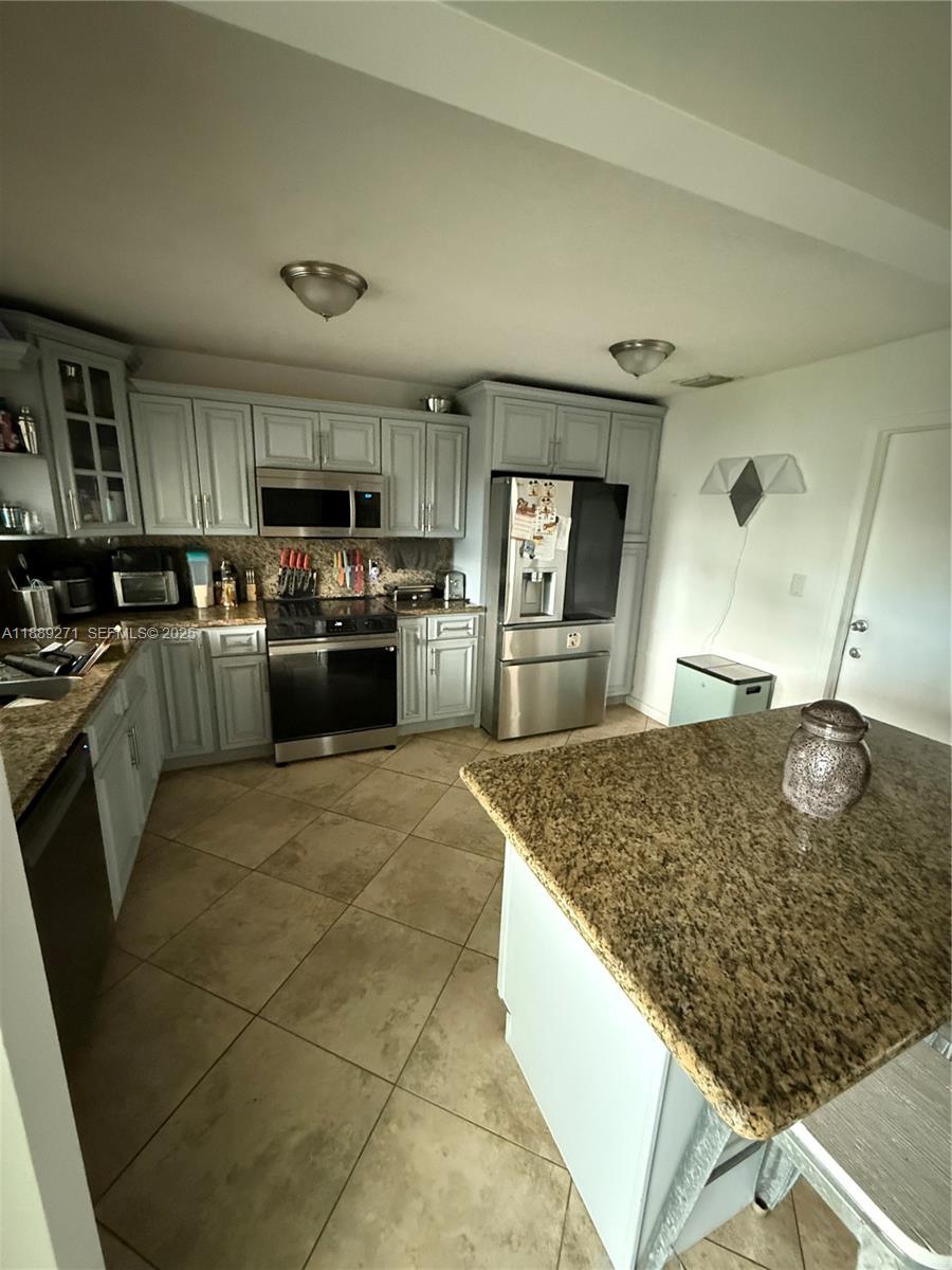 13060 Southwest 263rd Terrace Homestead, FL 33032 - Photo 9 of 30 a kitchen with kitchen island a sink refrigerator stove and microwave