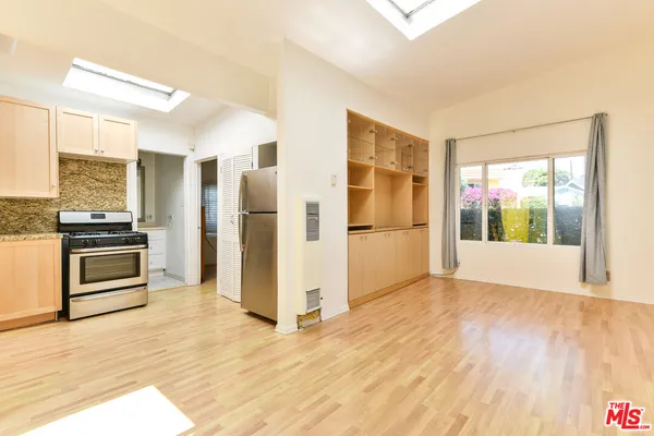 a view of kitchen with stainless steel appliances wooden floor and a window