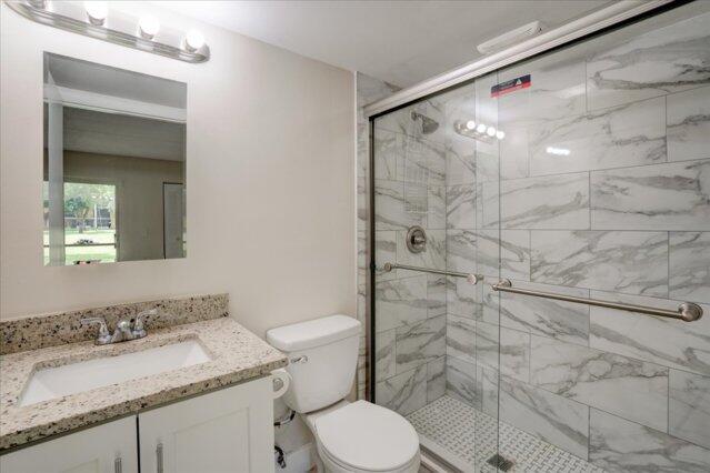 1104 Meadows Circle, Unit 1104 Boynton Beach, FL 33436 - Photo 23 of 27 a bathroom with a granite countertop sink toilet and shower