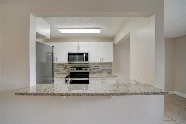 1104 Meadows Circle, Unit 1104 Boynton Beach, FL 33436 - Photo 3 of 27 a kitchen with granite countertop a sink and a stove top oven
