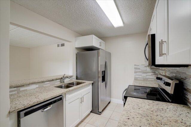 1104 Meadows Circle, Unit 1104 Boynton Beach, FL 33436 - Photo 6 of 27 a kitchen with a sink stove and refrigerator