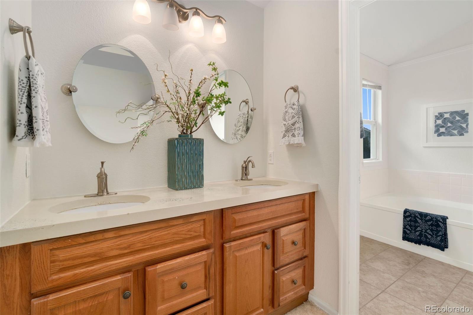 9752 Quay Loop Westminster, CO 80021 - Photo 17 of 27 a bathroom with a granite countertop sink a mirror and vanity