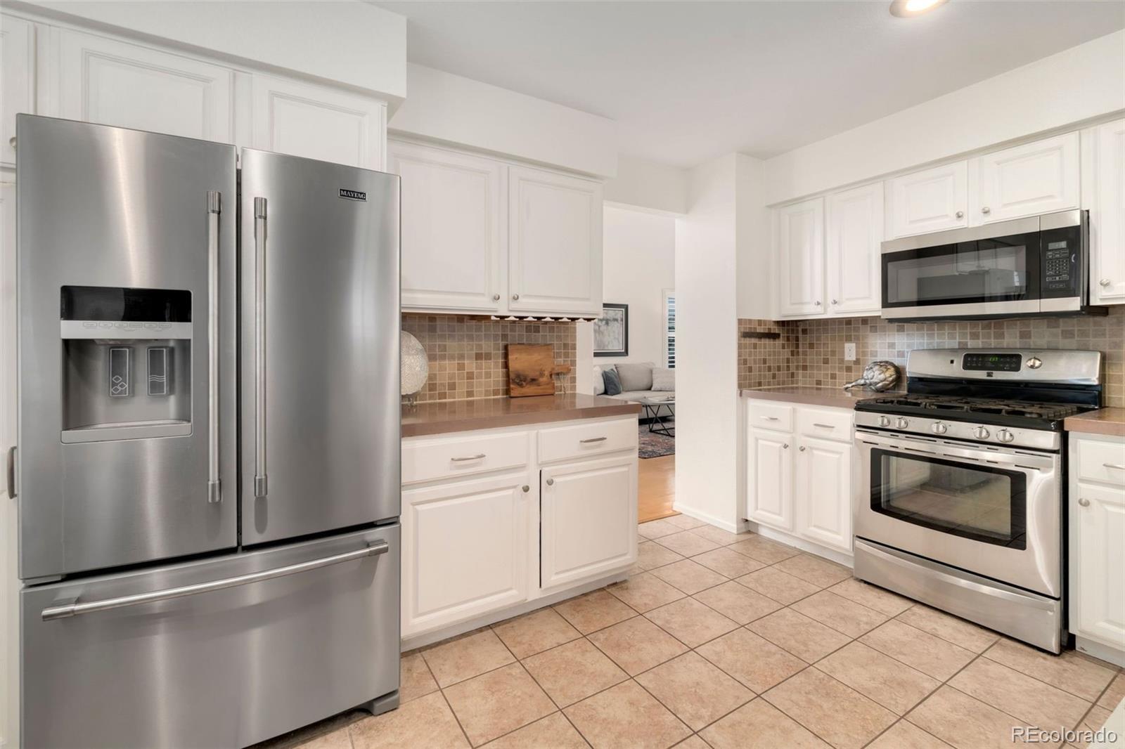 9752 Quay Loop Westminster, CO 80021 - Photo 9 of 27 a kitchen with stainless steel appliances granite countertop a refrigerator stove a sink and a microwave