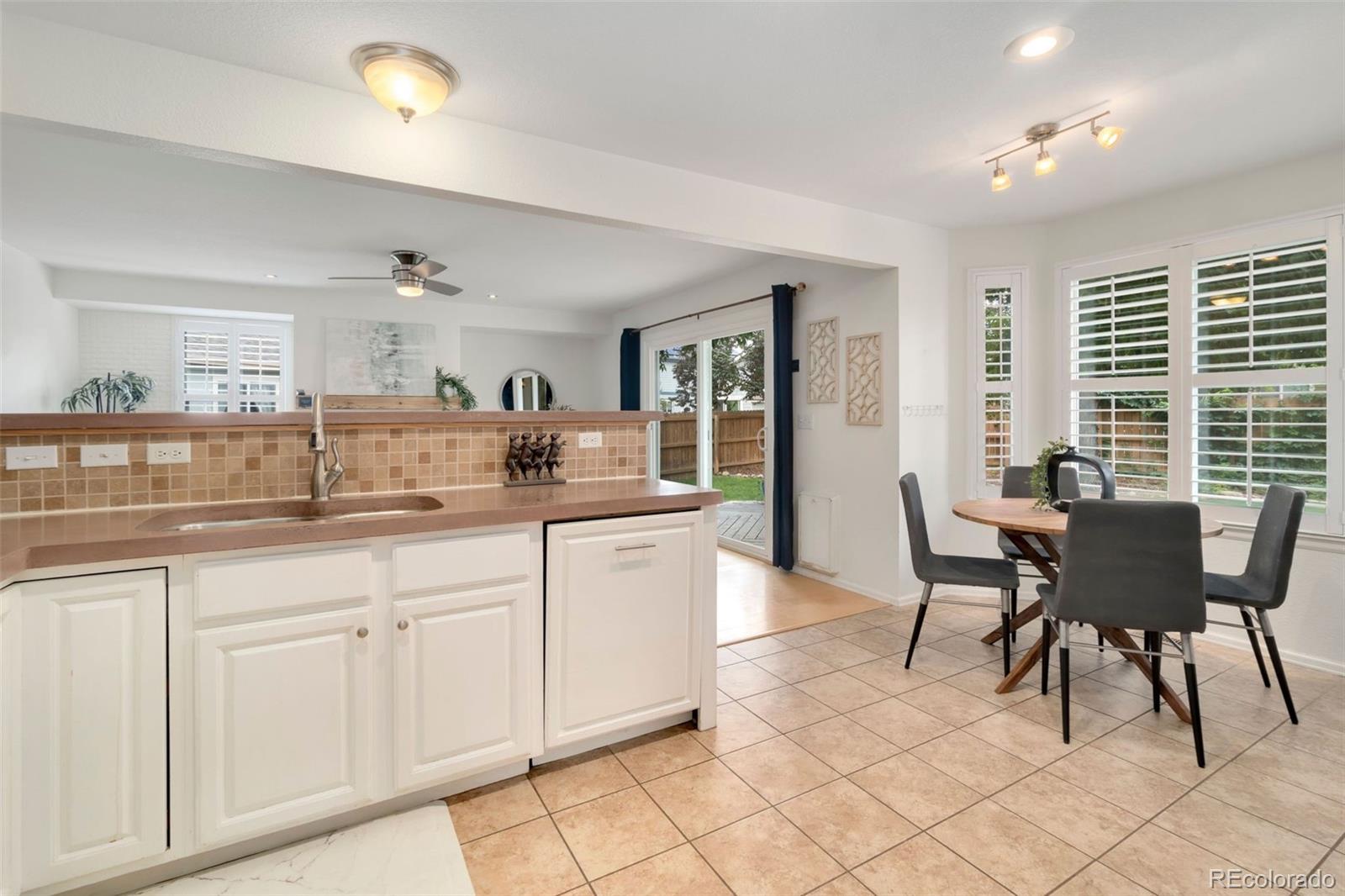 9752 Quay Loop Westminster, CO 80021 - Photo 10 of 27 a kitchen with granite countertop white cabinets dining table and chairs