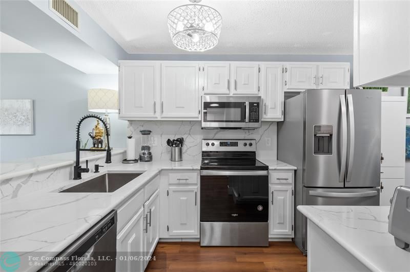 a kitchen with stainless steel appliances granite countertop a sink stove a refrigerator and cabinets with wooden floor