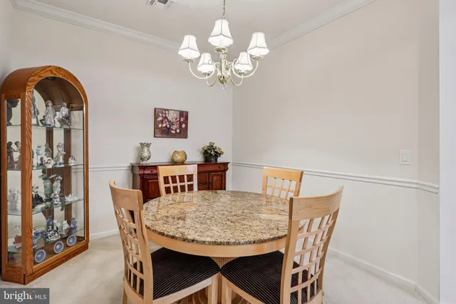 a dining room with wooden floor a chandelier a wooden table and chairs