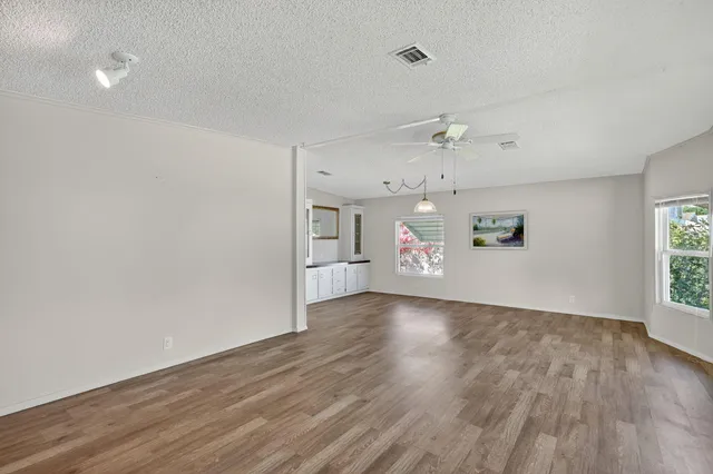 a view of empty room with wooden floor and a ceiling fan