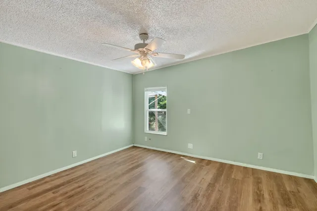 an empty room with wooden floor and a ceiling fan