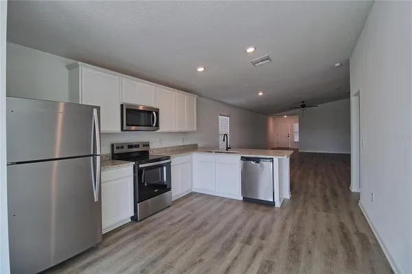 a kitchen with a refrigerator a stove top oven and wooden floor