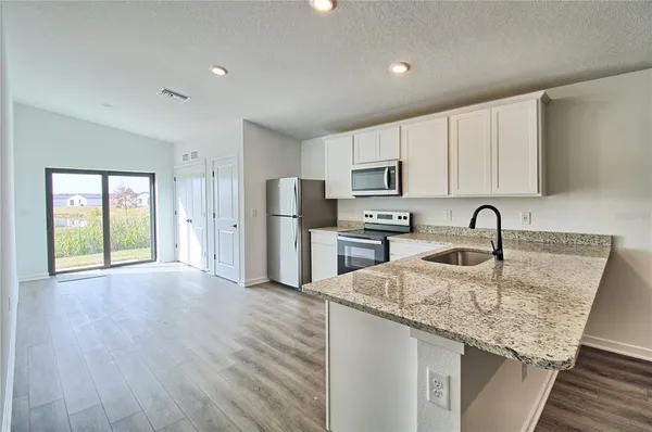 a kitchen with stainless steel appliances granite countertop a sink dishwasher a refrigerator and a stove with wooden floor