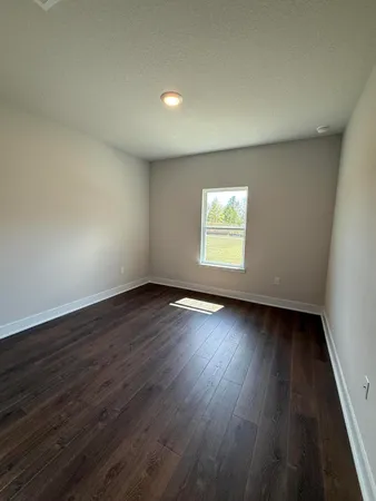 a view of an empty room with wooden floor and window