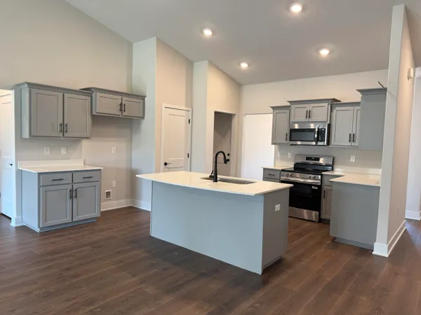 a kitchen with stainless steel appliances a sink dishwasher a refrigerator and a stove with wooden floors